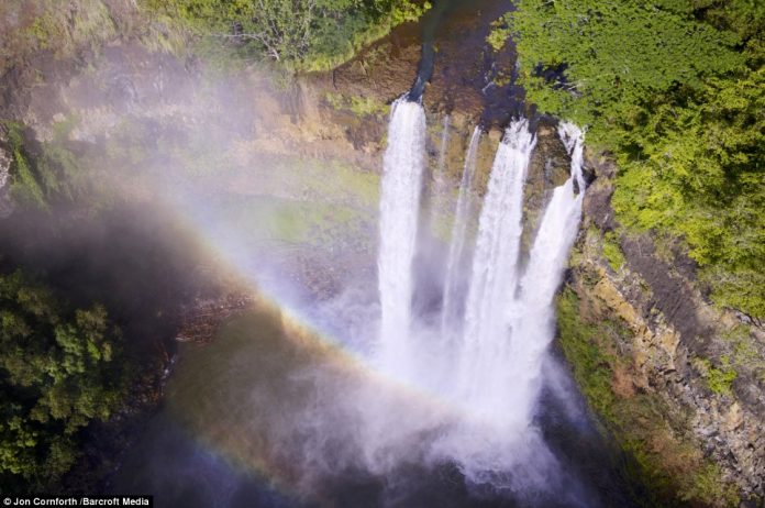A rainbow arrows into Wailua Falls at sunrise, all captured using the drone